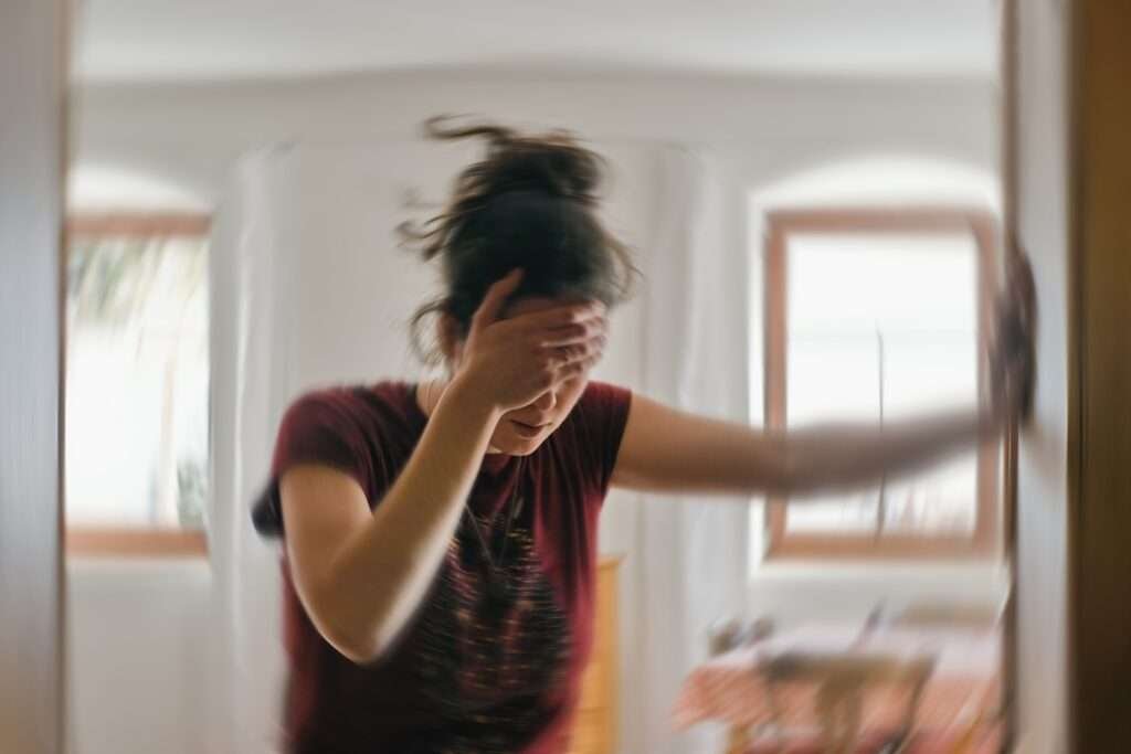Woman holding her head as the room appears to spin during a vertigo episode